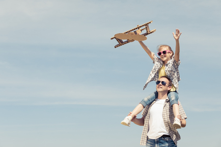 Father and daughter playing with cardboard toy airplane in the park at the day time. Concept of friendly family. People having fun outdoors. Picture made on the background of blue sky.の写真素材
