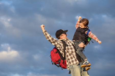 Father and son walking on the field at the day time. People having fun outdoors. Concept of friendly family.の写真素材