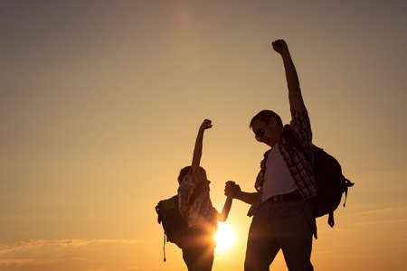 Father and son walking on the field at the sunset time. People having fun outdoors. Concept of friendly family.の写真素材