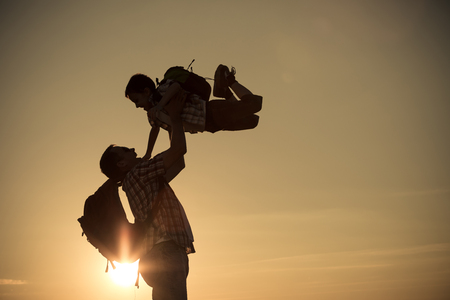 Father and son walking on the field at the sunset time. Concept of friendly family.の写真素材
