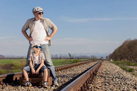 Father and son walking with suitcases on the railway at the day time. People having fun outdoors. Concept of friendly family.の写真素材