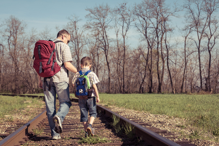 Father and son walking on the railway at the day time. People having fun outdoors. Concept of friendly family.の写真素材