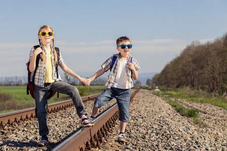 Happy brother and sister walking on the railway at the day time. People having fun outdoors. Concept of friendly family.の写真素材