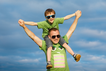 Father and son walking on the road at the day time. People having fun outdoors. Concept of friendly family.の写真素材