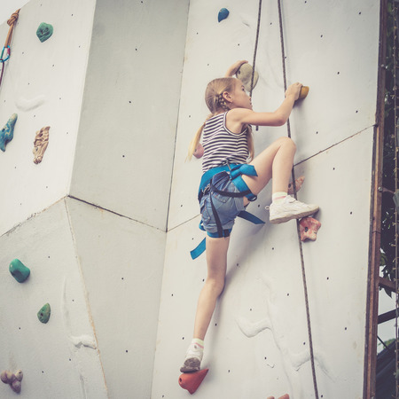 little girl climbing a rock wall outdoor. Concept of sport life.の写真素材