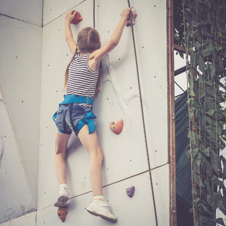 little girl climbing a rock wall outdoor. Concept of sport life.の写真素材