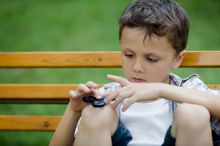 Happy little boy playing in the park at the day time. He playing with spinner. Kid having fun on the nature. Concept of happiness.の写真素材
