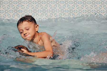 Two happy children playing on the swimming pool at the day time. People having fun outdoors. Concept of friendly siblings.の写真素材