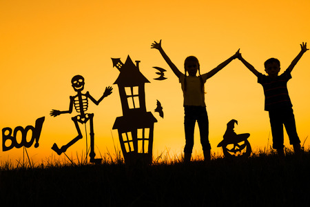 Happy brother and  sister playing outdoors at the sunset time. Kids having fun. Concept of happy Halloween party.の写真素材