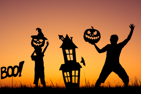 Happy father and son playing outdoors at the sunset time. People having fun. Concept of happy Halloween party.の写真素材