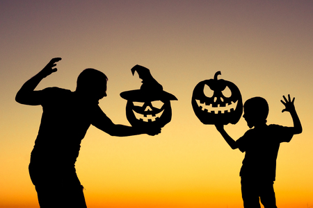 Happy father and son playing outdoors at the sunset time. People having fun. Concept of happy Halloween party.の写真素材