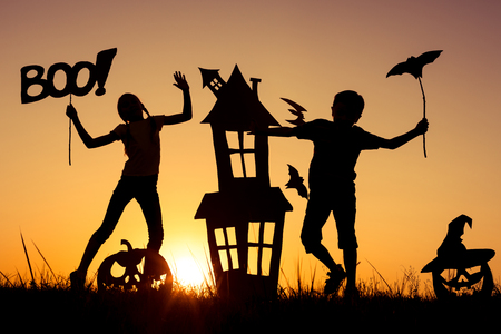 Happy brother and  sister playing outdoors at the sunset time. Kids having fun. Concept of happy Halloween party.の写真素材