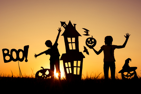 Happy brother and  sister playing outdoors at the sunset time. Kids having fun. Concept of happy Halloween party.の写真素材