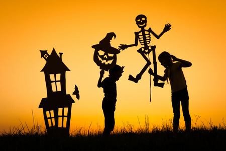 Happy brother and  sister playing outdoors at the sunset time. Kids having fun. Concept of happy Halloween party.の写真素材
