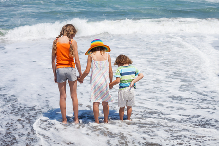 Three happy children playing on the beach at the day time. Concept of summer vacation.の写真素材