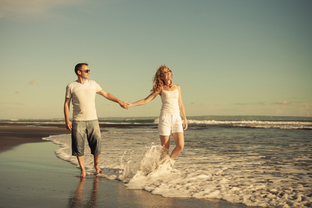 Romantic happy  man and woman couple walking on a  beach at the day timeの写真素材