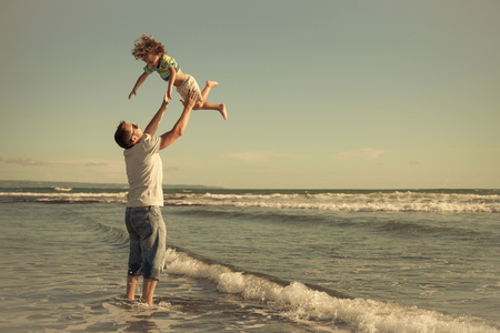 Father and son playing on the beach at the day time. People having fun outdoors. Concept of friendly family.の写真素材