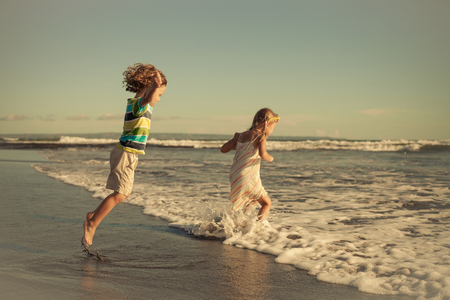 Two happy children playing on the beach at the day time. Concept of summer vacation.の写真素材