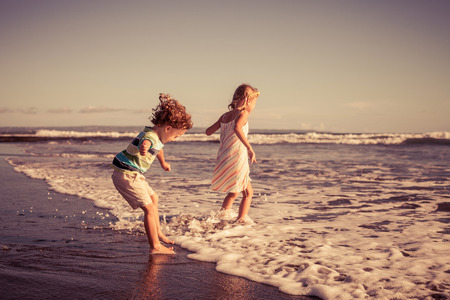 Two happy children playing on the beach at the day time. Concept of summer vacation.の写真素材