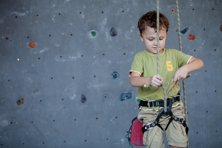 little boy standing near a climbing  rock wall indoor. Concept of sport life.の写真素材