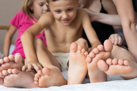 Happy brother and sisters  sitting on the bed barefoot. Concept of happiness.の写真素材