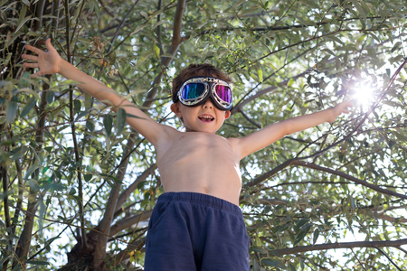 Happy little boy playing outdoors near a tree at the day time.の写真素材