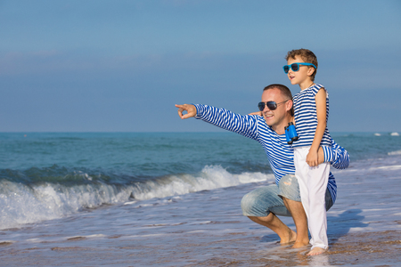 Father and son playing on the beach at the day time. They are dressed in sailor's vests. Concept of sailors on vacation and friendly family.の写真素材