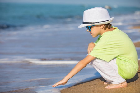 One happy little boy playing on the beach at the day time.  Kid having fun outdoors. Concept of summer vacation.の写真素材