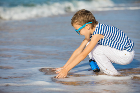 One happy little boy playing on the beach at the day time. He are dressed in sailor's vest. Kid having fun outdoors. Concept of sailor on vacation.の写真素材