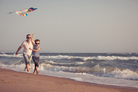 Father and son playing on the beach at the day time. People having fun outdoors. Concept of summer vacation and friendly family.の写真素材