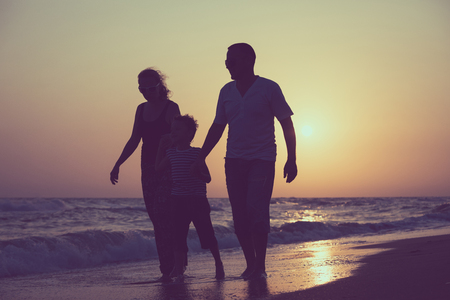 Father mother and son  playing on the beach at the sunset time. People having fun outdoors. Concept of summer vacation and friendly family.の写真素材