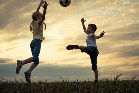 Happy young little boy and girl playing in the field  with soccer ball.  Kids having fun outdoors. Concept of sport.の写真素材