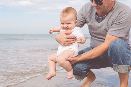 Father and son playing on the beach at the day time. People having fun outdoors. Concept of summer vacation and friendly family.の写真素材