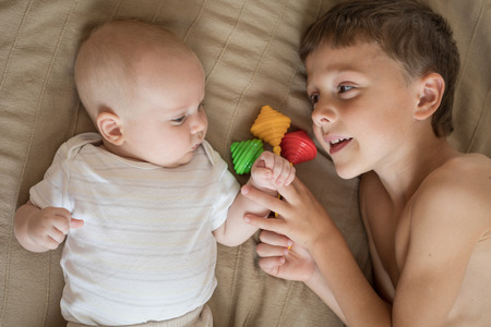little boy playing with newborn on the bed  at the day timeの写真素材