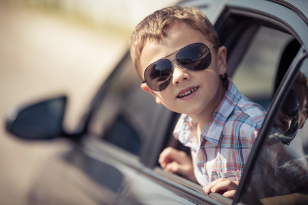 One happy little boy sitting in the car at the day time. Concept of summer vacation.の写真素材