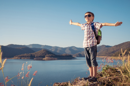 One happy little boy standing near a lake at the day time. Kid having fun outdoors. Concept of summer vacation and happy camp.の写真素材