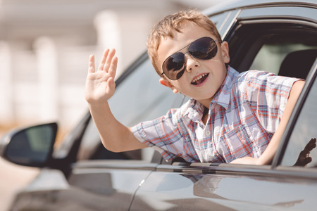 One happy little boy sitting in the car at the day time. Concept of summer vacation.の写真素材