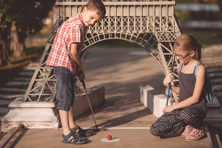 Happy brother and sisters  playing mini golf in a park at the day time. People having fun otdoors. Concept of good leisure.の写真素材