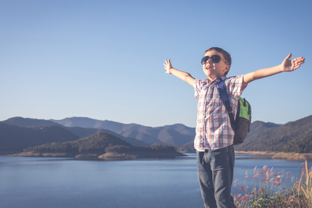 One happy little boy standing near a lake at the day time. Kid having fun outdoors. Concept of summer vacation and happy camp.の写真素材