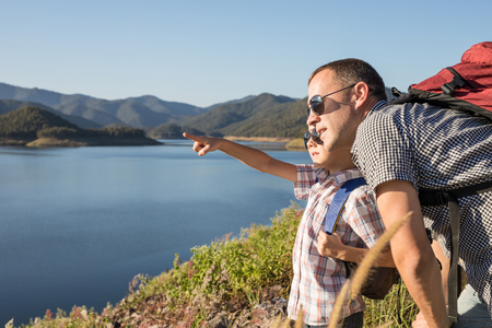Happy father and son standing near a lake at the day time. Concept of friendly family.の写真素材