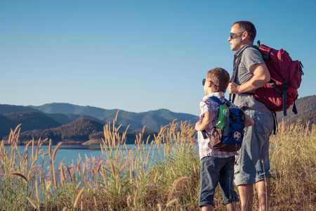 Happy father and son standing near a lake at the day time. Concept of friendly family.の写真素材
