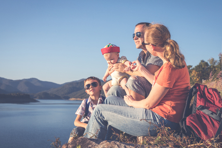Happy family sitting near the lake at the day time. Concept of friendly family.の写真素材