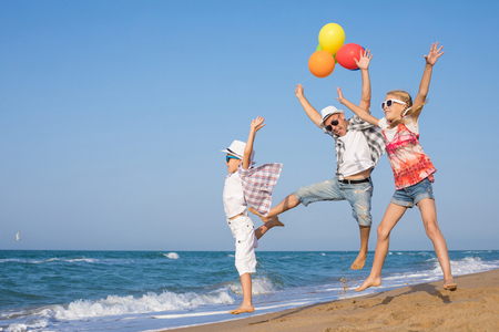 Father and son and daughter playing on the beach at the day time. People having fun outdoors. Concept of summer vacation and friendly family.の写真素材