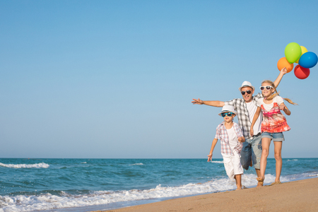 Father and son and daughter playing on the beach at the day time. People having fun outdoors. Concept of summer vacation and friendly family.の写真素材