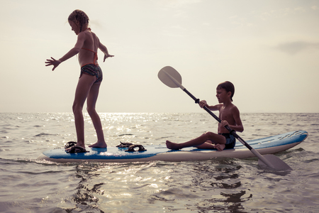 Happy children playing on the beach at the day time.Two Kids having fun outdoors. Concept of summer vacation and friendly family.の写真素材