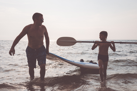 Father and son playing on the beach at the day time. People having fun outdoors. Concept of summer vacation and friendly family.の写真素材