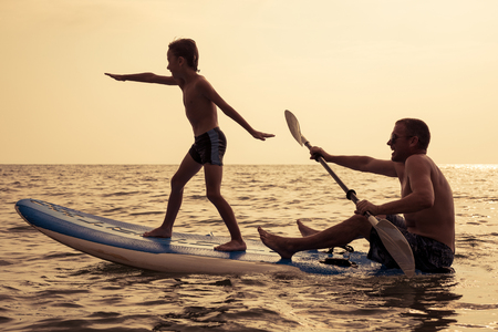 Father and baby son playing on the beach at the day time. People having fun outdoors. Concept of summer vacation and friendly family.の写真素材