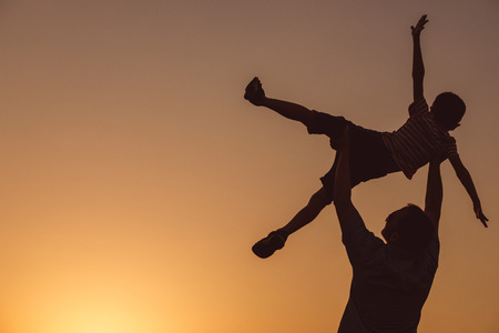 Father and son playing in the park at the sunset time. People having fun on the field. Concept of friendly family and of summer vacation.の写真素材