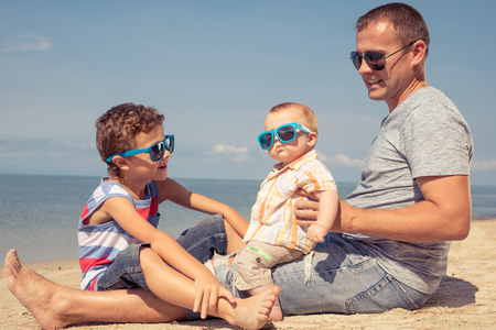 Father and  children playing on the beach at the summer day time. People having fun outdoors. Concept of summer vacation and friendly family.の写真素材