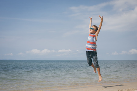 One happy little boy playing on the beach at the day time.  Kid having fun outdoors. Concept of summer vacation.の写真素材